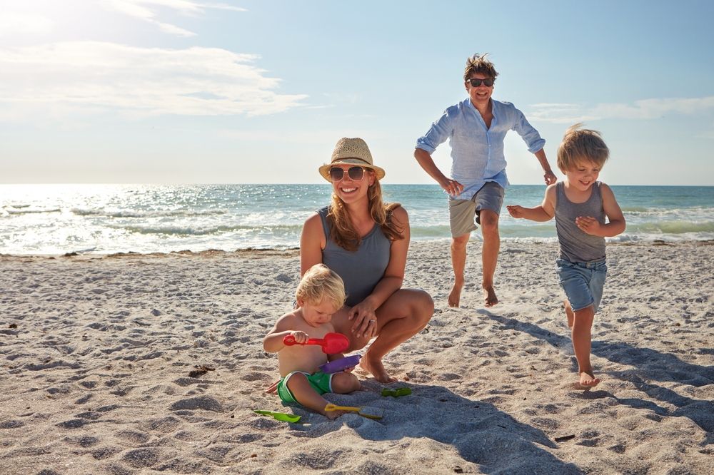 family playing on the beach in the summer.