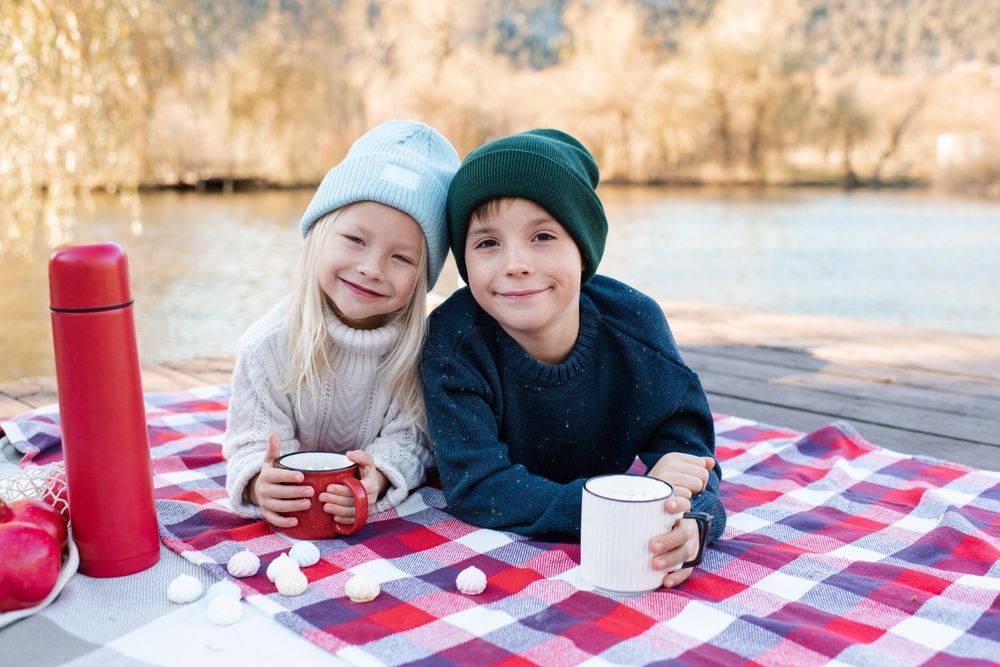 Two kids boy and girl 4-5 year old having picnic on wooden deck.